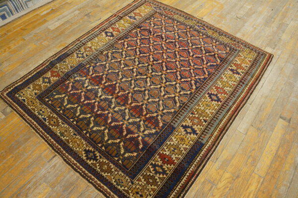 Navy blue, rust, and gold geometric rug with multiple borders displayed on wide plank wood floors.