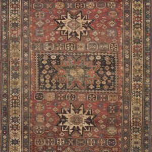 Faded red rug with complex geometric designs, featuring a large dark blue central panel and multi-layered border.