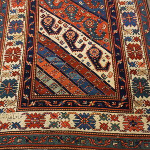 Geometric runner rug with a diagonal striped field pattern in rust, navy, cream, and teal on wooden floors.