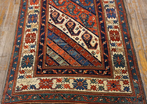 Geometric runner rug with a diagonal striped field pattern in rust, navy, cream, and teal on wooden floors.