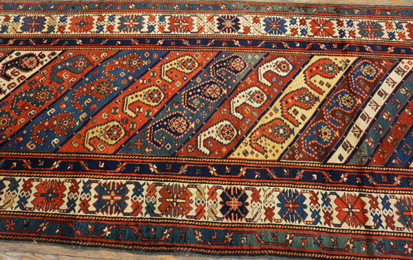 Rust, navy, and cream low-pile runner rug with a central diagonal pattern of alternating paisley motifs.