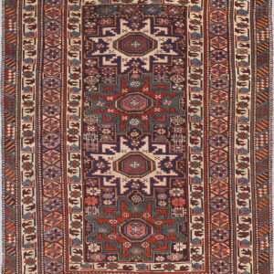 A low-pile geometric rug with complex borders and central motifs in red, navy, teal, and cream.