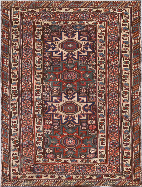 A low-pile geometric rug with complex borders and central motifs in red, navy, teal, and cream.