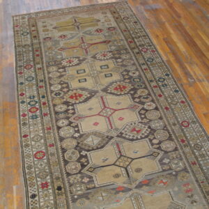Muted runner rug with intricate beige, gray, and dark brown geometric patterns on a wooden plank floor.