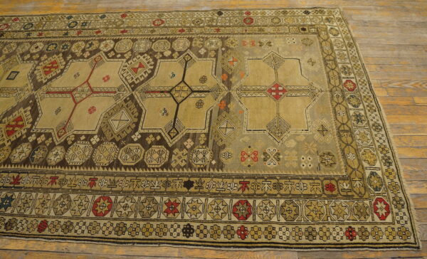 Muted geometric rug with khaki, brown, and red accents displaying large star patterns on wood flooring.