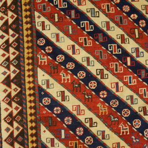Red, navy, and cream rug detail showing diagonal stripes, geometric hooked symbols, and small stylized horses.