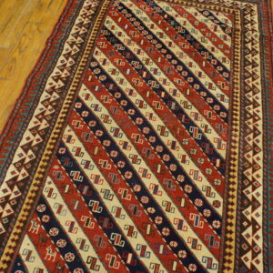 Low-pile runner with strong diagonal stripes of red, cream, and navy geometric designs on hardwood.