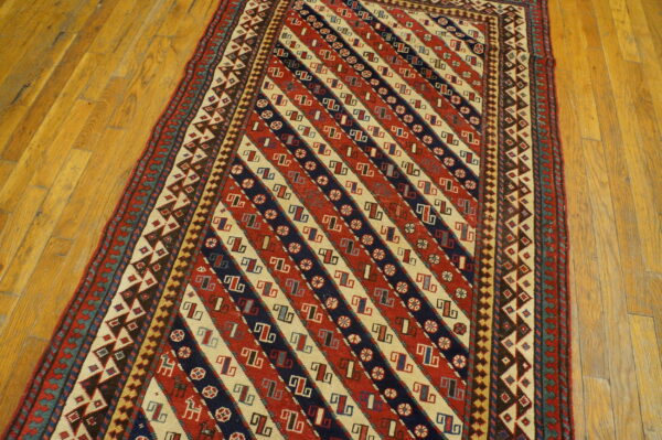 Low-pile runner with strong diagonal stripes of red, cream, and navy geometric designs on hardwood.