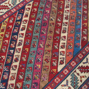 Multi-colored flatweave rug with dense geometric vertical stripes framed by contrasting patterned borders.