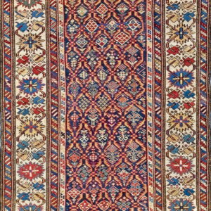 Navy and red geometric runner rug with diamond patterns and stylized floral medallions on a cream border.