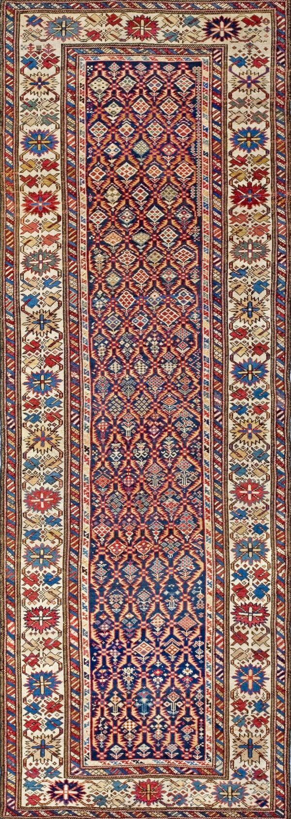 Navy and red geometric runner rug with diamond patterns and stylized floral medallions on a cream border.