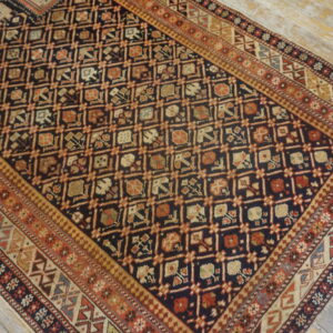 Dark navy rug with complex repeating geometric patterns and multi-layered borders on distressed wood floors.