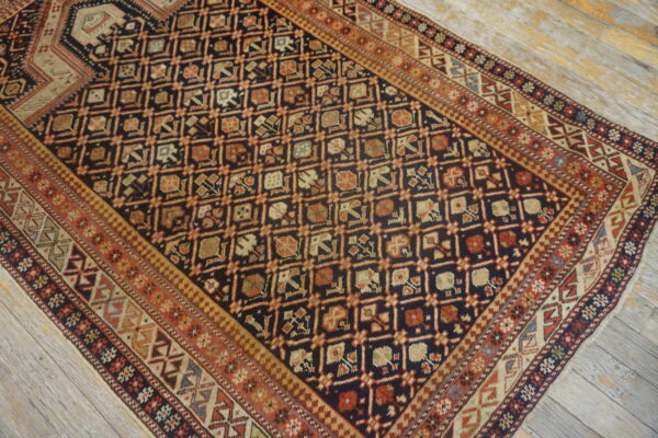 Dark navy rug with complex repeating geometric patterns and multi-layered borders on distressed wood floors.