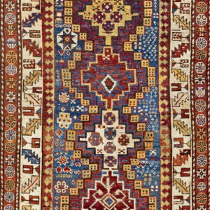 A geometric rug with a stepped medallion pattern in red, blue, cream, and yellow.