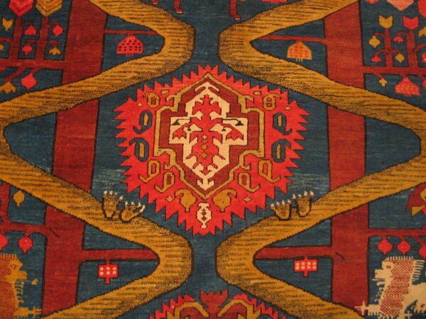 Detailed view of a low pile rug featuring tribal motifs in teal, deep red, gold, and cream colors.