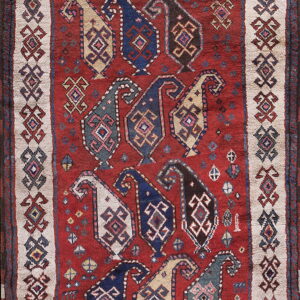 Deep red rug featuring staggered rows of multicolored geometric boteh shapes surrounded by a cream border.