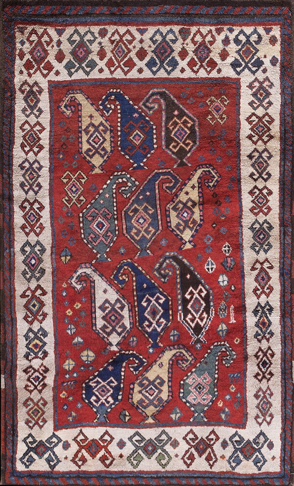 Deep red rug featuring staggered rows of multicolored geometric boteh shapes surrounded by a cream border.