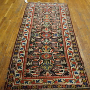 Geometric runner rug in red, black, blue, and cream colors displayed on polished hardwood floors.