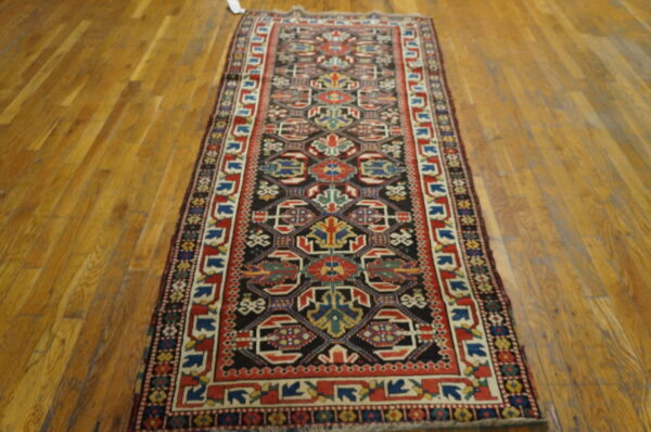Geometric runner rug in red, black, blue, and cream colors displayed on polished hardwood floors.