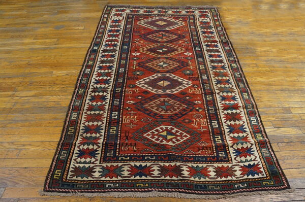 Red runner rug with geometric diamond medallions and navy borders lies on polished wood flooring.