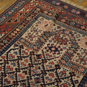 Low-texture rug corner with cream, red, and navy geometric tribal patterns on a wooden floor.