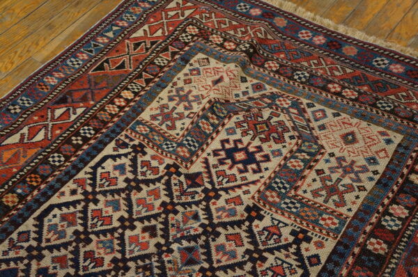 Low-texture rug corner with cream, red, and navy geometric tribal patterns on a wooden floor.