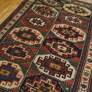 Geometric red, navy, and green rug with repeating medallions displayed on light hardwood.