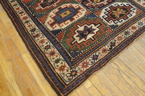 Low-pile rug with geometric patterns in red, navy, green, and cream on light wood flooring.