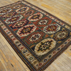 Rug with tribal octagonal patterns in rust, navy, green, and cream on worn light wood planks.