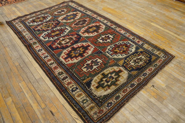Rug with tribal octagonal patterns in rust, navy, green, and cream on worn light wood planks.