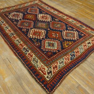 Navy blue and red geometric rug featuring tribal medallions displayed on worn wooden plank flooring.