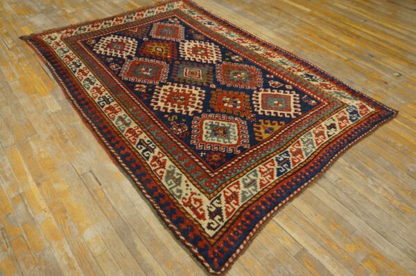 Navy blue and red geometric rug featuring tribal medallions displayed on worn wooden plank flooring.