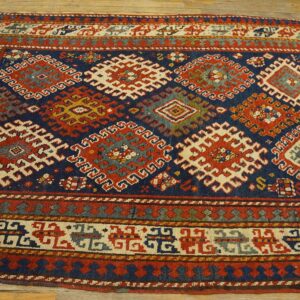 Detailed tribal rug in deep blue, red, and cream with complex geometric patterns on wood flooring.