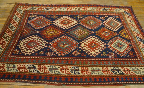Detailed tribal rug in deep blue, red, and cream with complex geometric patterns on wood flooring.