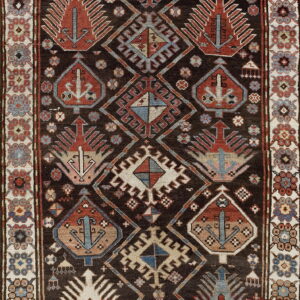 Dark tribal rug with red and blue geometric medallions framed by a cream floral border.