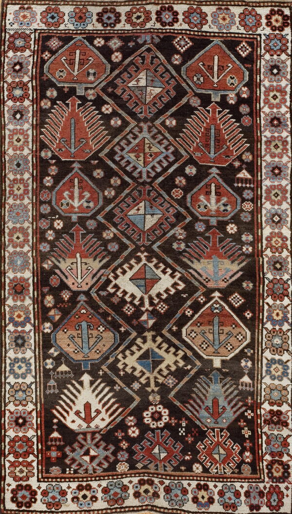 Dark tribal rug with red and blue geometric medallions framed by a cream floral border.
