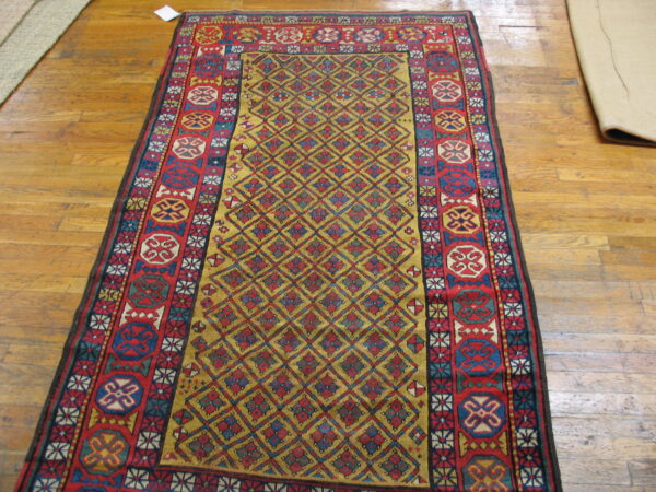 A long, low-pile red, gold, and blue geometric rug rests upon light brown hardwood floors.