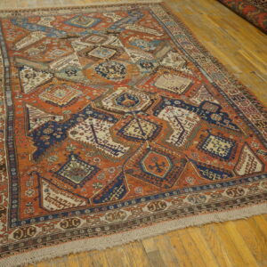 Orange and navy tribal geometric rug with low pile displayed on bright yellow-toned wooden floor planks.