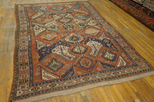 Orange and navy tribal geometric rug with low pile displayed on bright yellow-toned wooden floor planks.