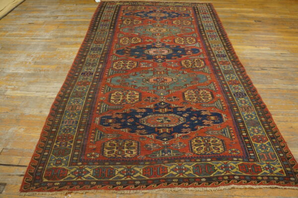 Geometric runner rug in deep red, navy, teal, and yellow on wide, distressed wooden floorboards.