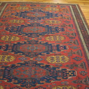 Red and navy geometric runner rug featuring repeated central medallions on light wood flooring.