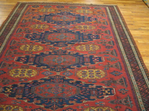 Red and navy geometric runner rug featuring repeated central medallions on light wood flooring.