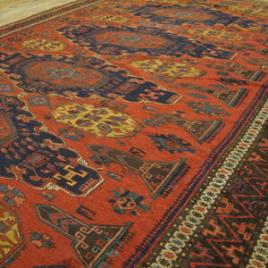 High contrast red rug with stylized navy and mustard geometric designs on a light wood floor.