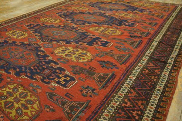 High contrast red rug with stylized navy and mustard geometric designs on a light wood floor.