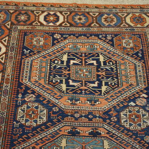 A densely patterned rug in navy, rust, and beige with a large geometric medallion rests on wood flooring.