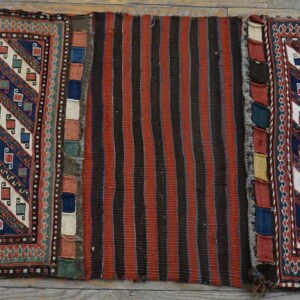 A geometric rug with diagonal motifs and a central striped panel rests on rustic wood flooring.