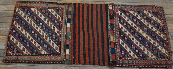 A geometric rug with diagonal motifs and a central striped panel rests on rustic wood flooring.