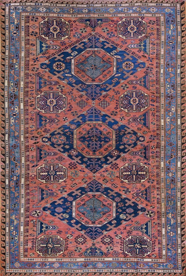 Geometric tribal rug in deep navy and reddish-orange with multiple intricate patterned borders.