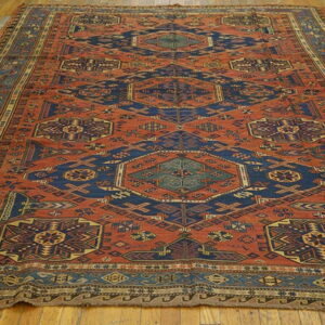 A large geometric rug featuring rust, navy, and teal colors with central medallions on a wood plank floor.