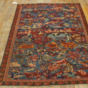 Low-pile runner rug with complex blue, red, and earth-toned abstract designs over yellow hardwood.